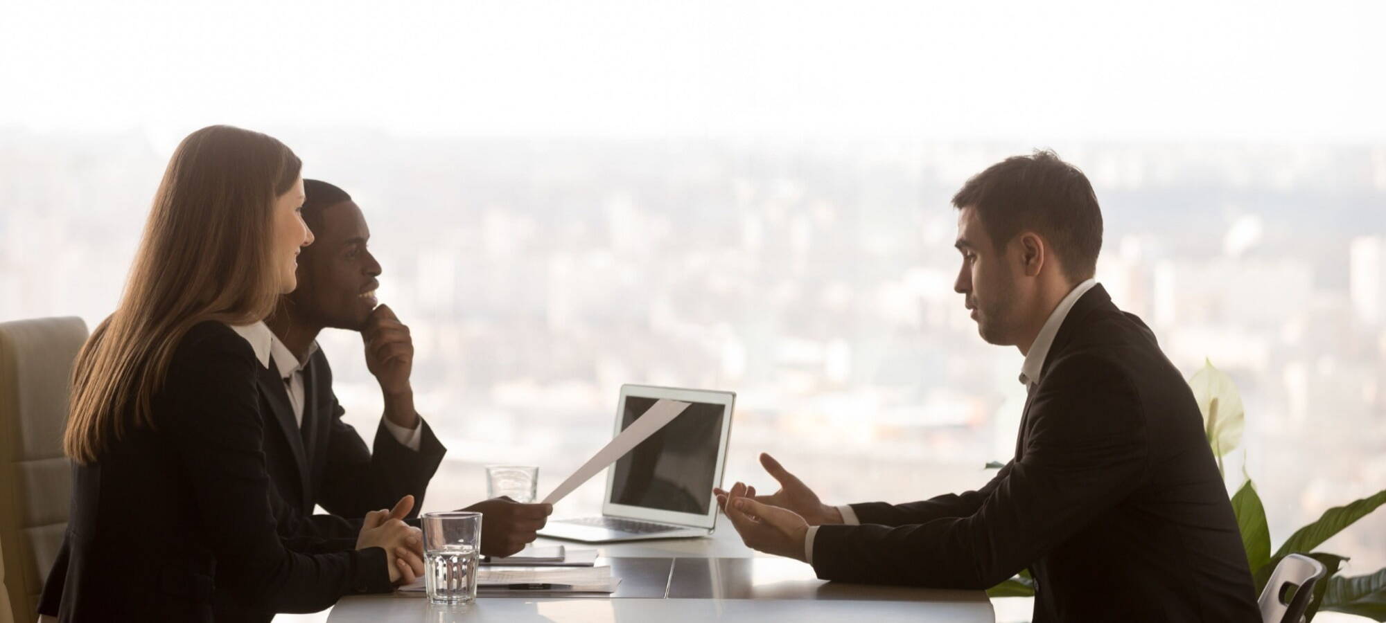 A man and women interview a young man in a smart-looking office.